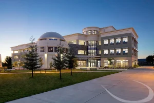 Modesto Junior College Science Community Center, a modern academic building with a domed observatory, illuminated at dusk.