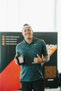 Man holding a prize bottle and smiling at Iron Mechanical’s Annual Golf Tournament celebration.