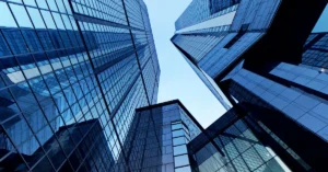 Upward view of modern glass skyscrapers reflecting the sky, symbolizing high-rise commercial buildings with advanced indoor air quality and HVAC infrastructure.