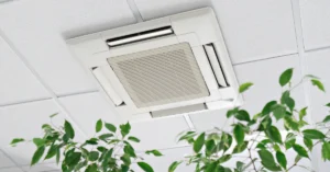 Ceiling-mounted air conditioning unit in a commercial space with indoor plants nearby, highlighting HVAC systems that support healthy indoor air quality.