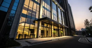 Modern commercial building entrance with floor-to-ceiling glass windows and illuminated interior, showcasing upscale tenant improvement design.