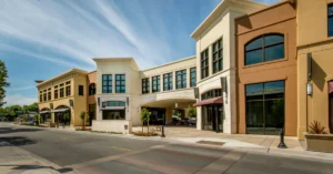 Contemporary commercial retail plaza with large windows, stucco facades, and pedestrian-friendly design, showcasing modern tenant improvement architecture.