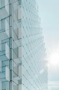 Modern glass commercial building exterior with sunlight reflecting off the facade.