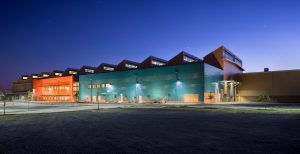 ACE Maintenance Facility, a large industrial building with colorful exterior walls, illuminated at night.