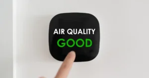 Close-up of a digital air quality monitor displaying “Air Quality: Good” with a person’s finger pointing, indicating healthy indoor environmental conditions.