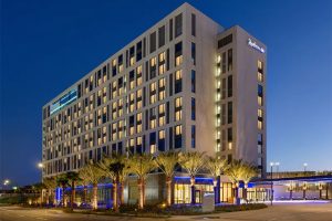Radisson Blu Anaheim hotel at night, featuring modern architecture, illuminated palm trees, and a sleek exterior.