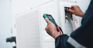 A technician uses a multimeter to test an HVAC unit's electrical components.