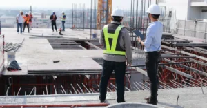 Construction site with workers and engineers wearing safety gear, discussing plans for a CALGreen modular construction project in Sacramento, highlighting sustainable building practices.